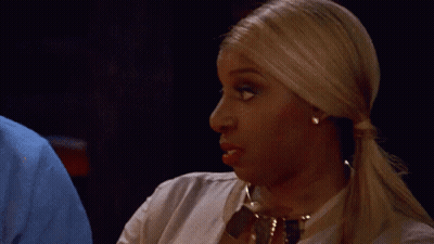A Woman With Blonde Hair Is Wearing A White Shirt And Gold Necklace GIF