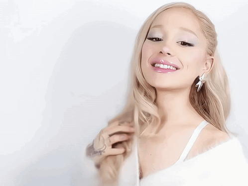 A Woman With Blonde Hair Is Wearing A White Top GIF