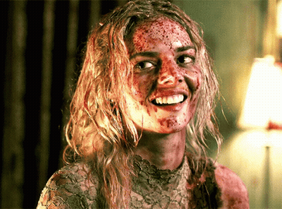 A Woman With Blood On Her Face Is Smiling And Looking At The Camera GIF