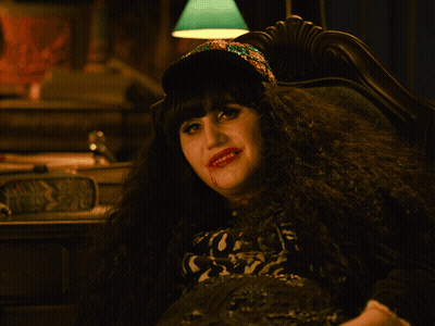 A Woman With Blood On Her Face Is Wearing A Hat And Making A Rock Sign GIF