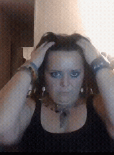 A Woman With Blue Eye Makeup Is Holding Her Head GIF