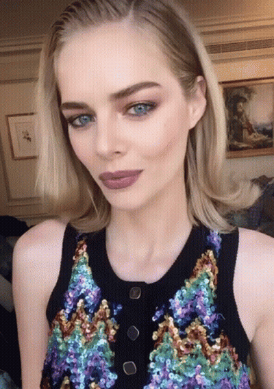 A Woman With Blue Eyes Is Wearing A Sequined Top With Buttons GIF