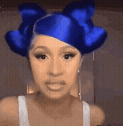 A Woman With Blue Hair And A Blue Bow In Her Hair Is Making A Funny Face . GIF