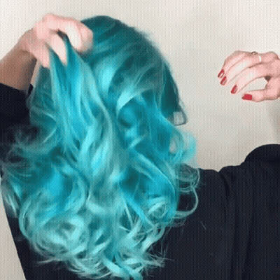 A Woman With Blue Hair And Red Nails Is Holding Her Hair GIF
