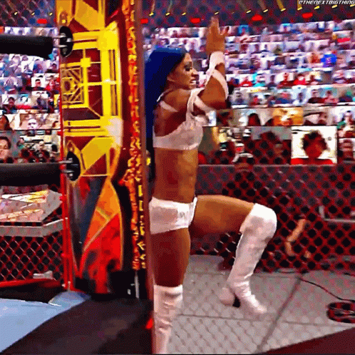 A Woman With Blue Hair And White Boots Is Standing In A Wrestling Ring With Her Leg Up . GIF