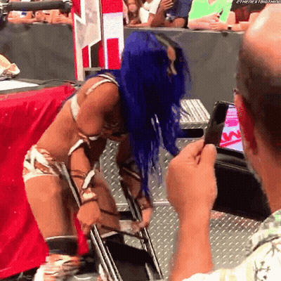 A Woman With Blue Hair Is Being Photographed By A Man With A Cell Phone GIF