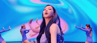 A Woman With Blue Hair Is Dancing On A Stage In Front Of A Crowd . GIF