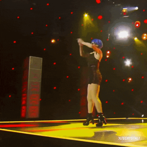 A Woman With Blue Hair Is Dancing On A Stage With Xtechystali Written On The Bottom GIF