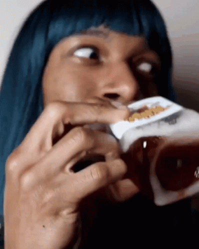 A Woman With Blue Hair Is Drinking From A Box Of Cereal GIF