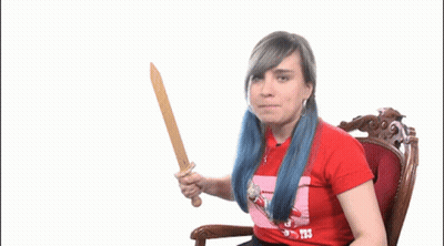A Woman With Blue Hair Is Holding A Wooden Sword And Wearing A Red Shirt That Says T3 GIF