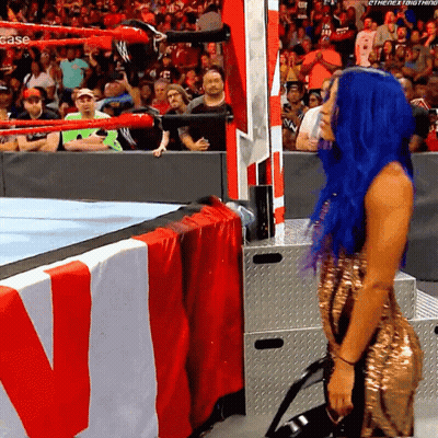 A Woman With Blue Hair Is Kneeling Down In Front Of A Wrestling Ring That Says Case On It GIF
