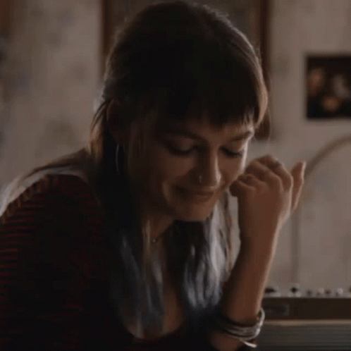 A Woman With Blue Hair Is Sitting At A Table With Her Hand On Her Chin . GIF