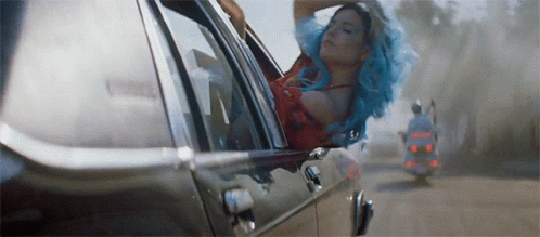 A Woman With Blue Hair Is Sitting In A Car . GIF