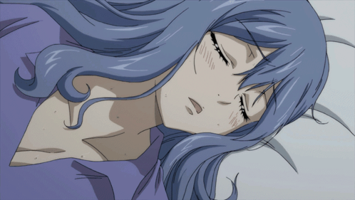 A Woman With Blue Hair Is Sleeping On A Bed With Her Eyes Closed GIF