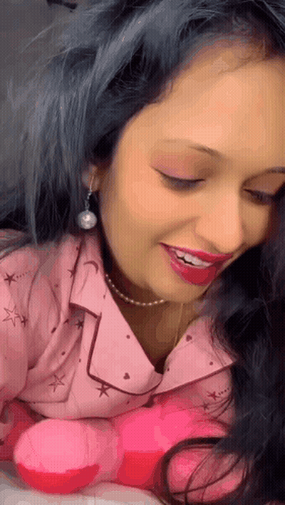 A Woman With Blue Hair Is Smiling And Holding A Pink Stuffed Animal GIF