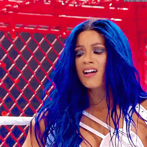 A Woman With Blue Hair Is Standing In Front Of A Red Fence . GIF