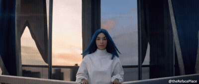 A Woman With Blue Hair Is Standing In Front Of A Window With The Words " Therefaceplace " Below Her GIF