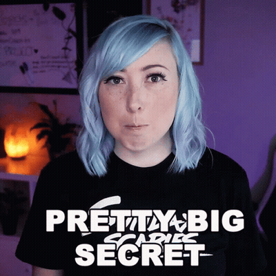 A Woman With Blue Hair Is Wearing A Black Shirt That Says Pretty Big Scare Secret GIF