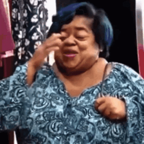 A Woman With Blue Hair Is Wearing A Blue Shirt And Making A Face . GIF