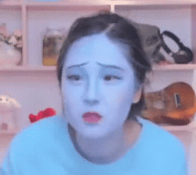A Woman With Blue Paint On Her Face Looks Sad . GIF