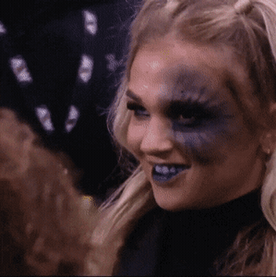 A Woman With Blue Paint On Her Face Smiles GIF