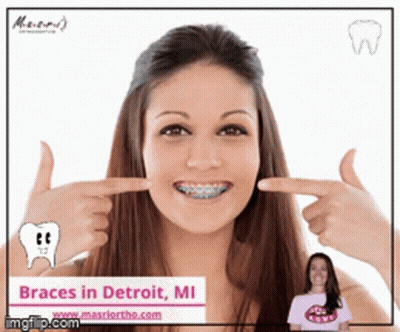 A Woman With Braces On Her Teeth Is Pointing At Her Teeth GIF