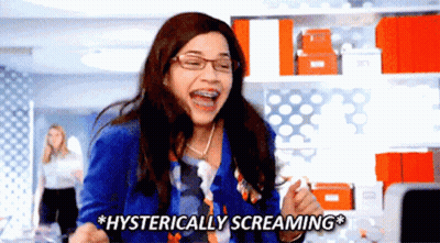 A Woman With Braces On Her Teeth Is Screaming Hysterically In An Office GIF