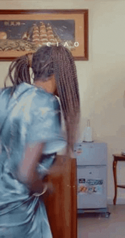 A Woman With Braids Is Dancing In A Living Room In Front Of A Painting Of A Ship . GIF