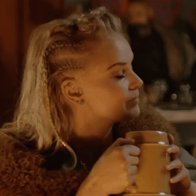 A Woman With Braids Is Holding A Mug Of Beer . GIF