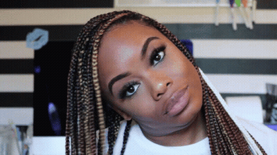 A Woman With Braids Is Looking At The Camera With A Striped Wall In The Background GIF