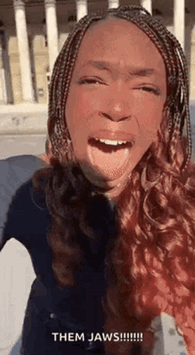 A Woman With Braids Is Making A Funny Face With Her Tongue Hanging Out . GIF