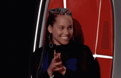 A Woman With Braids Is Sitting In A Chair Covering Her Mouth With Her Hand . GIF