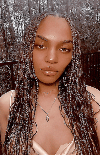 A Woman With Braids Is Wearing A Necklace With A Heart Pendant GIF
