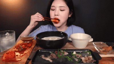 A Woman With Chopsticks Is Eating A Bowl Of Soup GIF