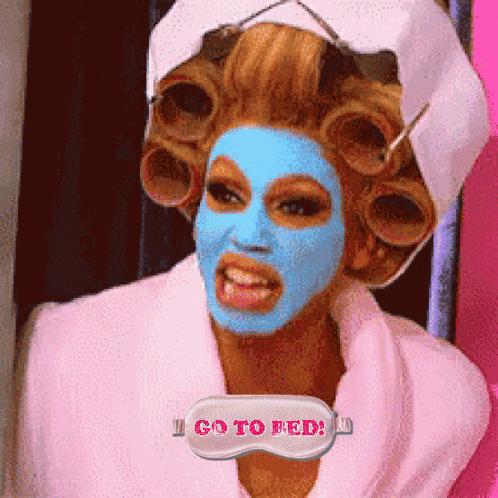 A Woman With Curlers On Her Head Has A Mask On Her Face That Says I Go To Feed GIF