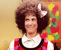 A Woman With Curly Hair And A Bow In Her Hair Is Smiling GIF