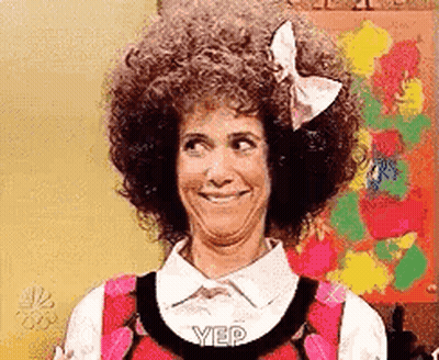 A Woman With Curly Hair And A Bow On Her Head Is Smiling And Making A Funny Face . GIF