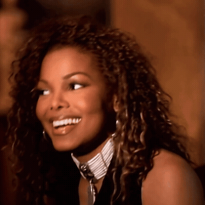 A Woman With Curly Hair And A Choker Smiles GIF