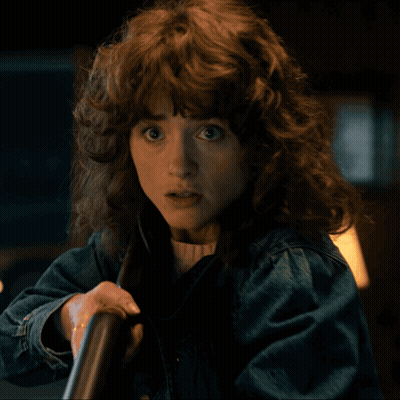 A Woman With Curly Hair And A Denim Jacket GIF