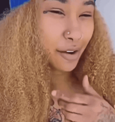 A Woman With Curly Hair And A Tattoo On Her Hand GIF