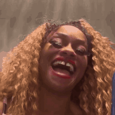 A Woman With Curly Hair And Red Lips Is Laughing GIF