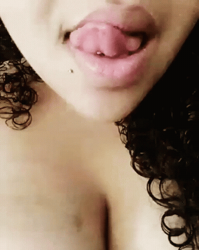 A Woman With Curly Hair Is Licking Her Lips GIF