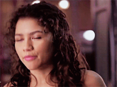 A Woman With Curly Hair Is Making A Funny Face GIF