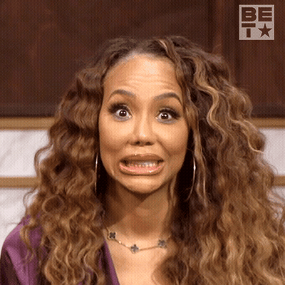 A Woman With Curly Hair Is Making A Funny Face While Wearing A Necklace . GIF
