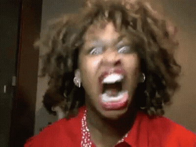 A Woman With Curly Hair Is Screaming With Her Mouth Open . GIF