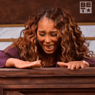 A Woman With Curly Hair Is Sitting At A Podium With A Be T Logo In The Background GIF
