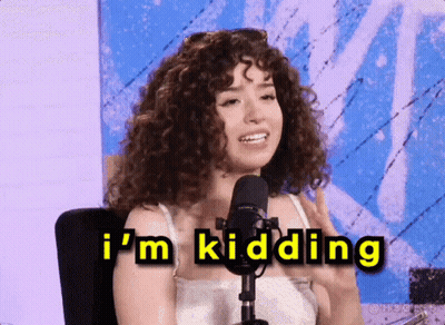 A Woman With Curly Hair Is Sitting In Front Of A Microphone And Says " I 'M Kidding " GIF