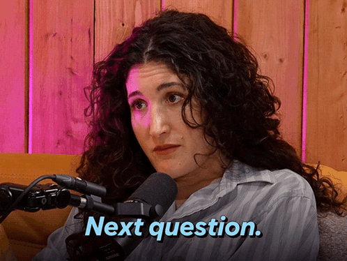 A Woman With Curly Hair Is Sitting In Front Of A Microphone And Says Next Question GIF