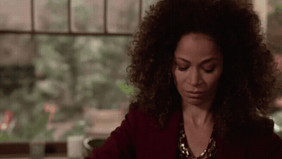 A Woman With Curly Hair Is Sitting In Front Of A Window With Her Eyes Closed . GIF