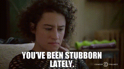 A Woman With Curly Hair Is Sitting On A Couch And Says You 'Ve Been Stubborn Lately .. GIF